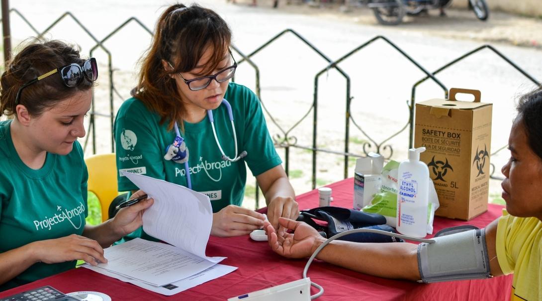 On the Public Health Group Internship in the Philippines, interns check the vital signs of people during an outreach. As part of the Projects Abroad Public Health group work in the Philippines, interns check the blood pressure of patents.